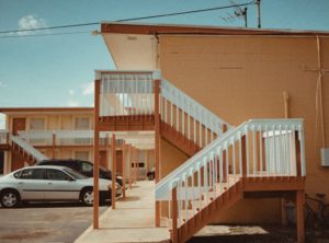 Side view of a motel with stairs and cars parked outside 