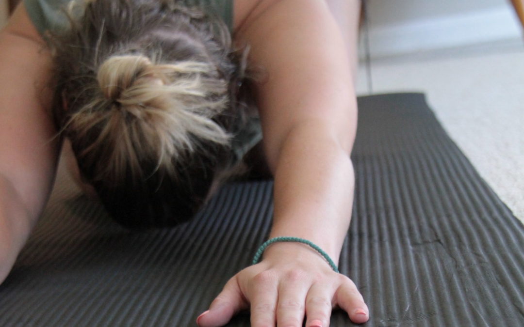 woman on a yoga mat is in child's pose