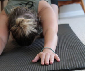 woman on a yoga mat is in child's pose